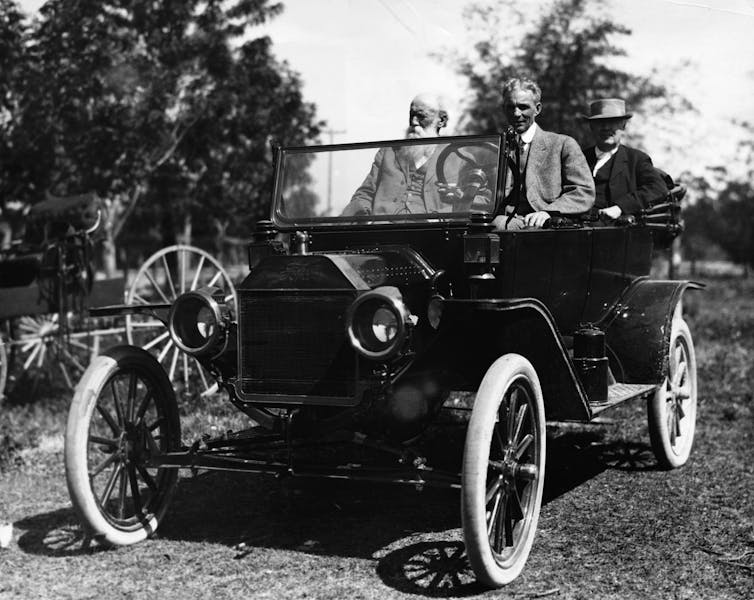 A black and white photo of two men in an old car.