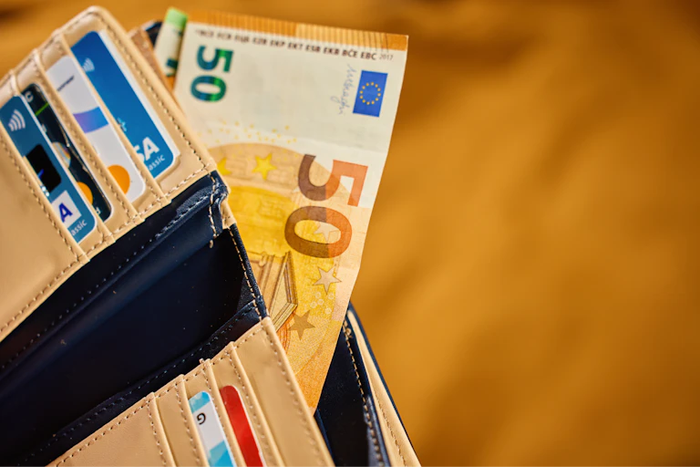 Une portefeuille avec des billets de banques et plusieurs cartes de crédit.