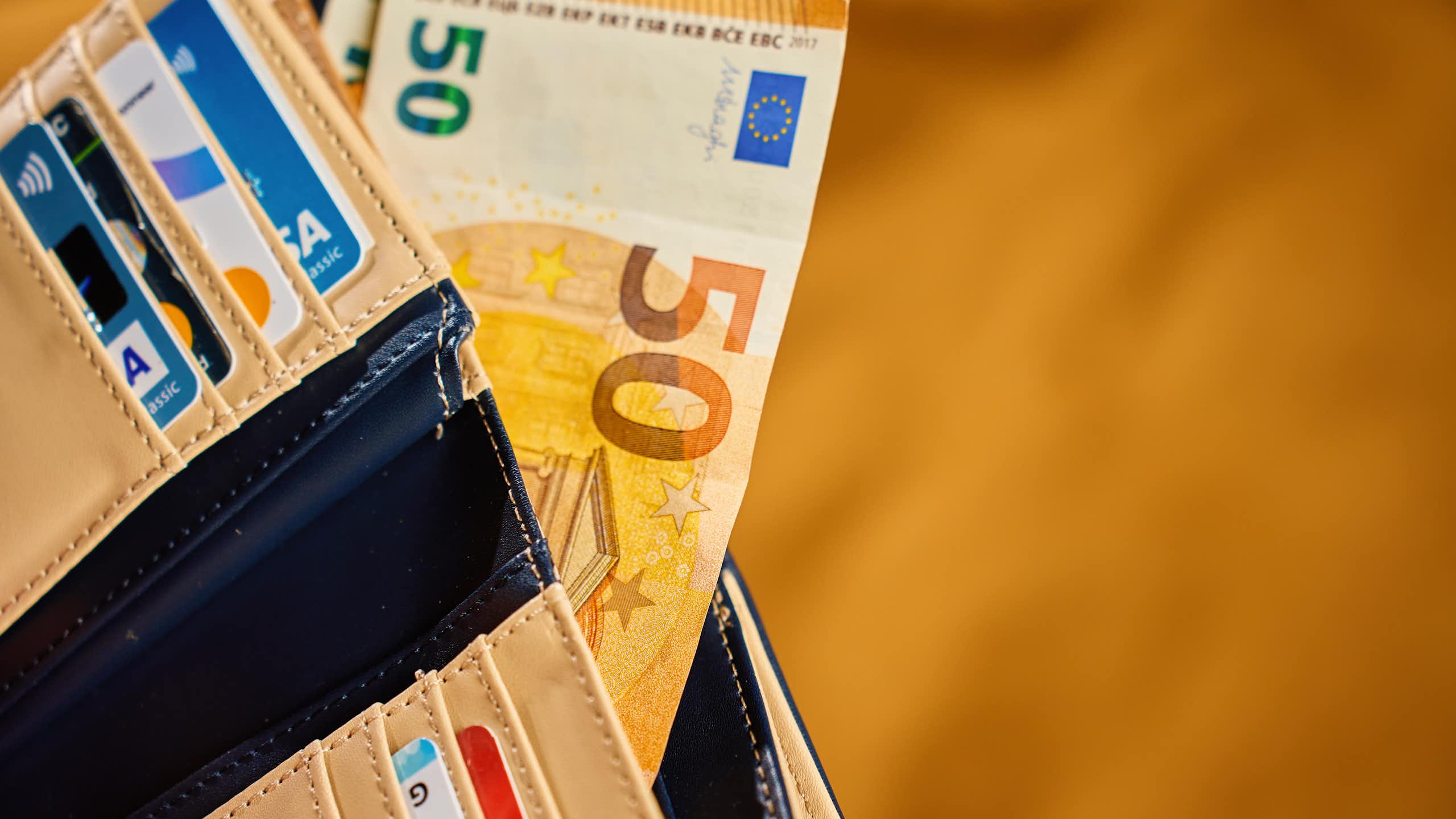 Une portefeuille avec des billets de banques et plusieurs cartes de crédit.