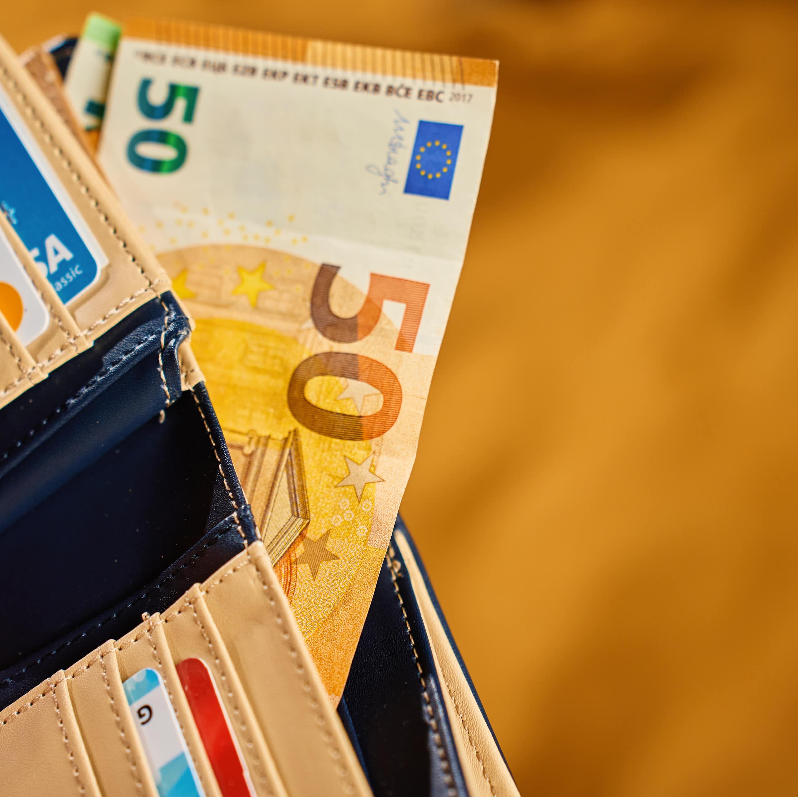 Une portefeuille avec des billets de banques et plusieurs cartes de crédit.