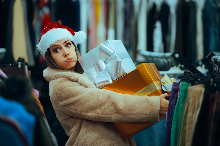 Woman carrying giftwrapped boxes, looking fatigued