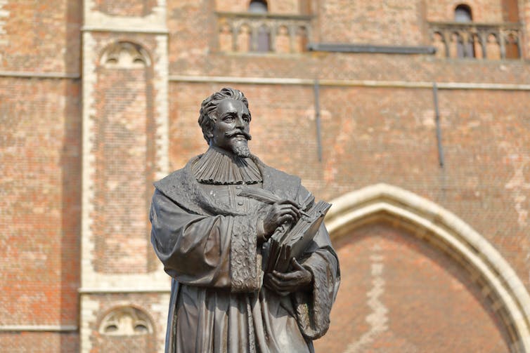 A statue of Hugo Grotius outside the Nieuwe Kerk clock tower in Delft.
