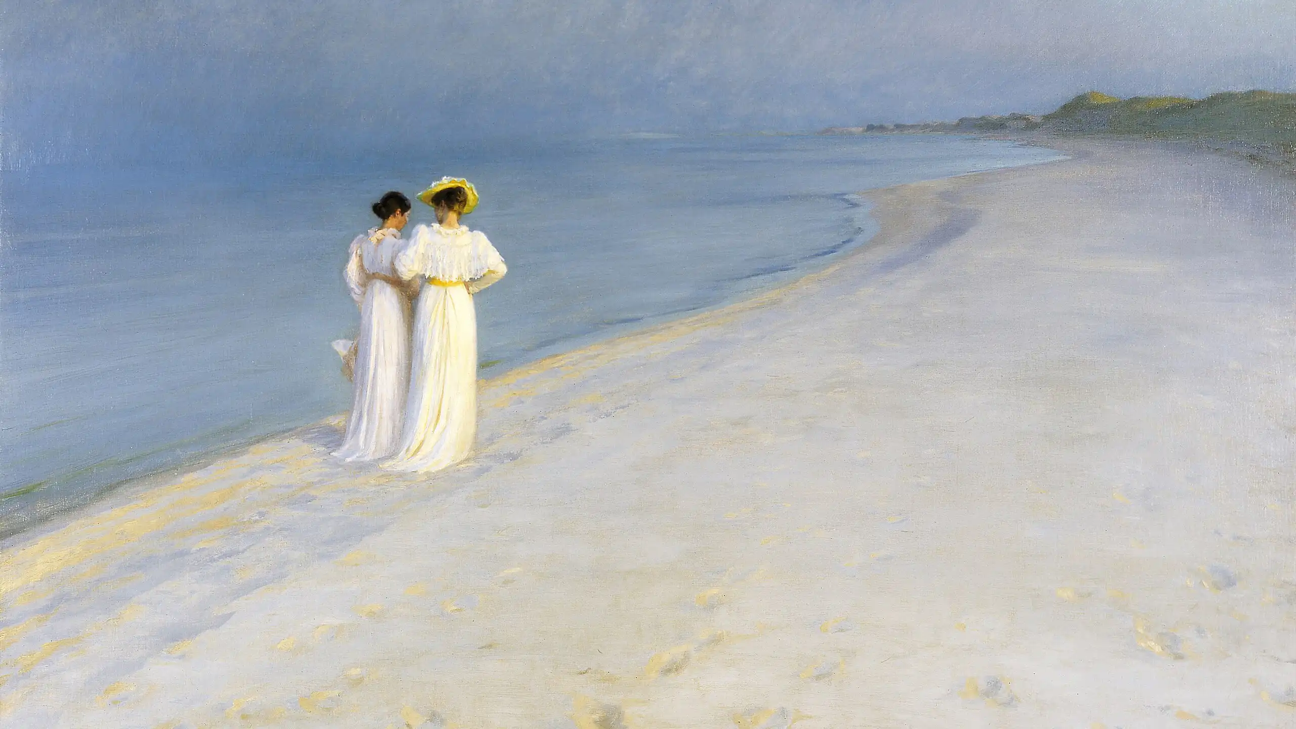 Two women walking down a beach arm in arm