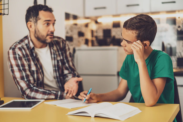 Un hombre habla con un joven que está estudiando.