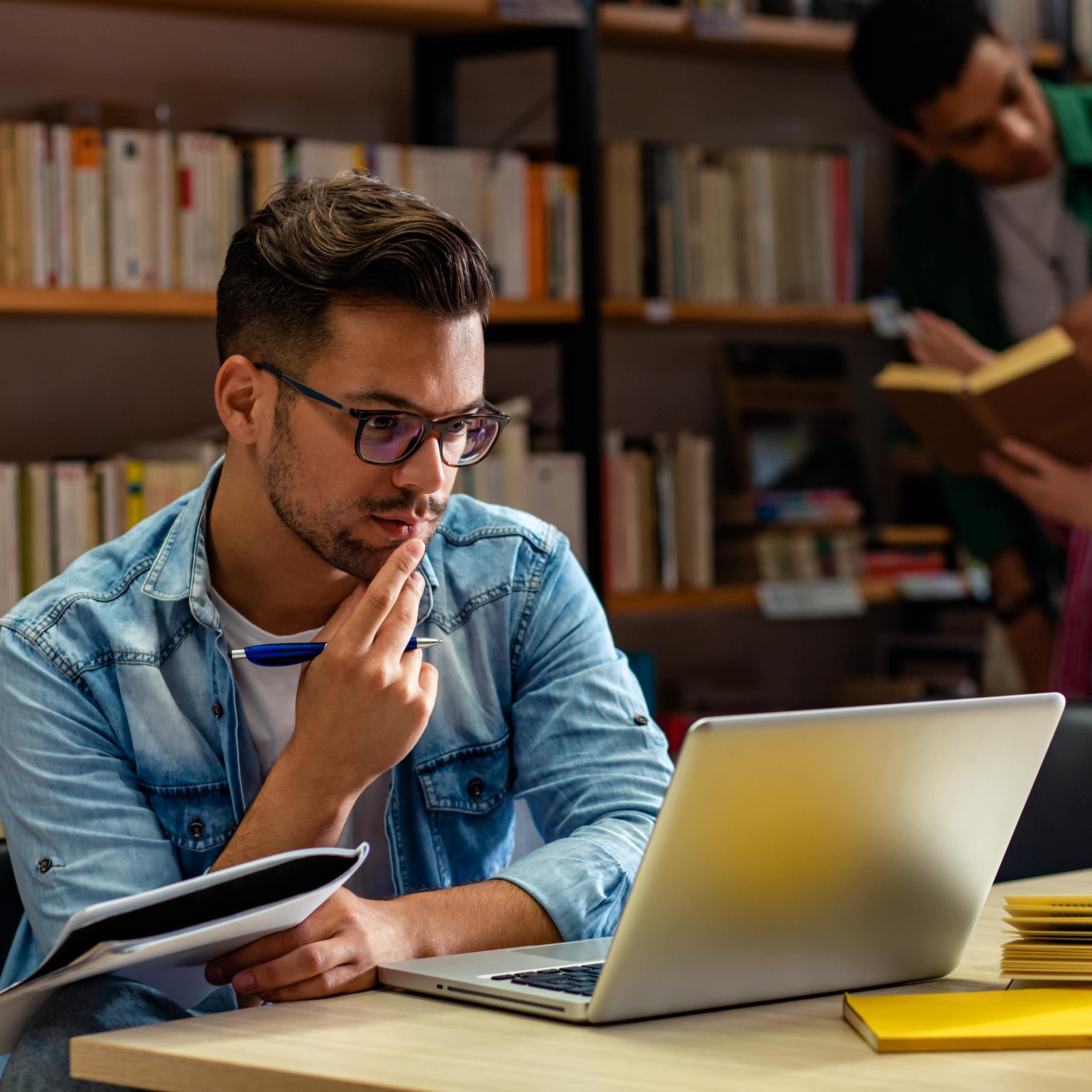 Un joven mira pensativo la pantalla de su portátil.