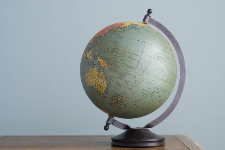 A globe sits atop a desk.