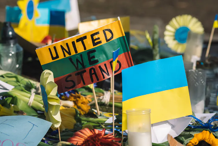 lithuanian flag with the message united we stand being held up alongside a ukrainian flat at a peaceful protest in vilnius