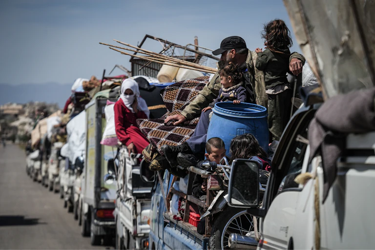 Mena and women crowd onto a convoy of vehicles.