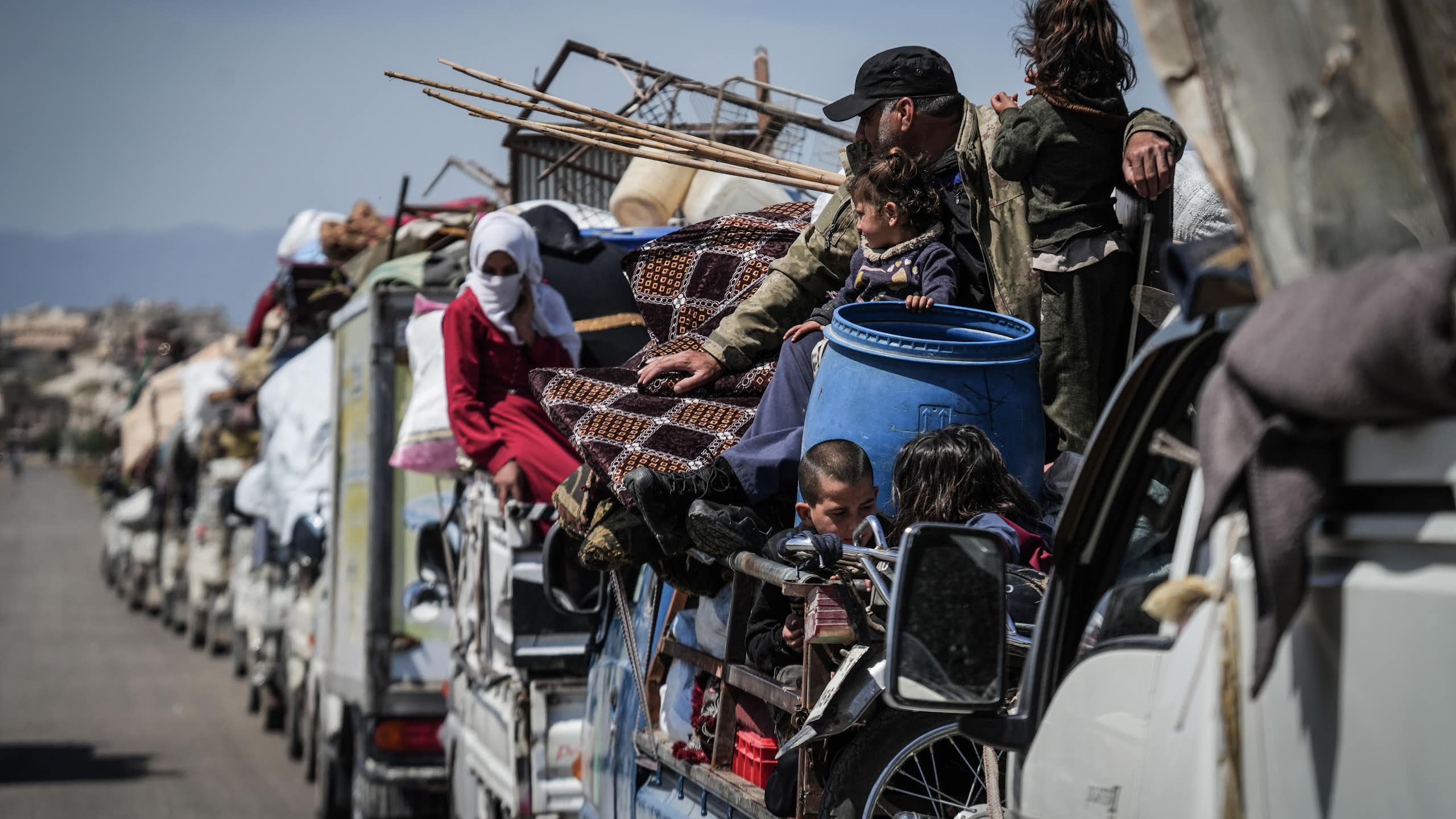 Mena and women crowd onto a convoy of vehicles.