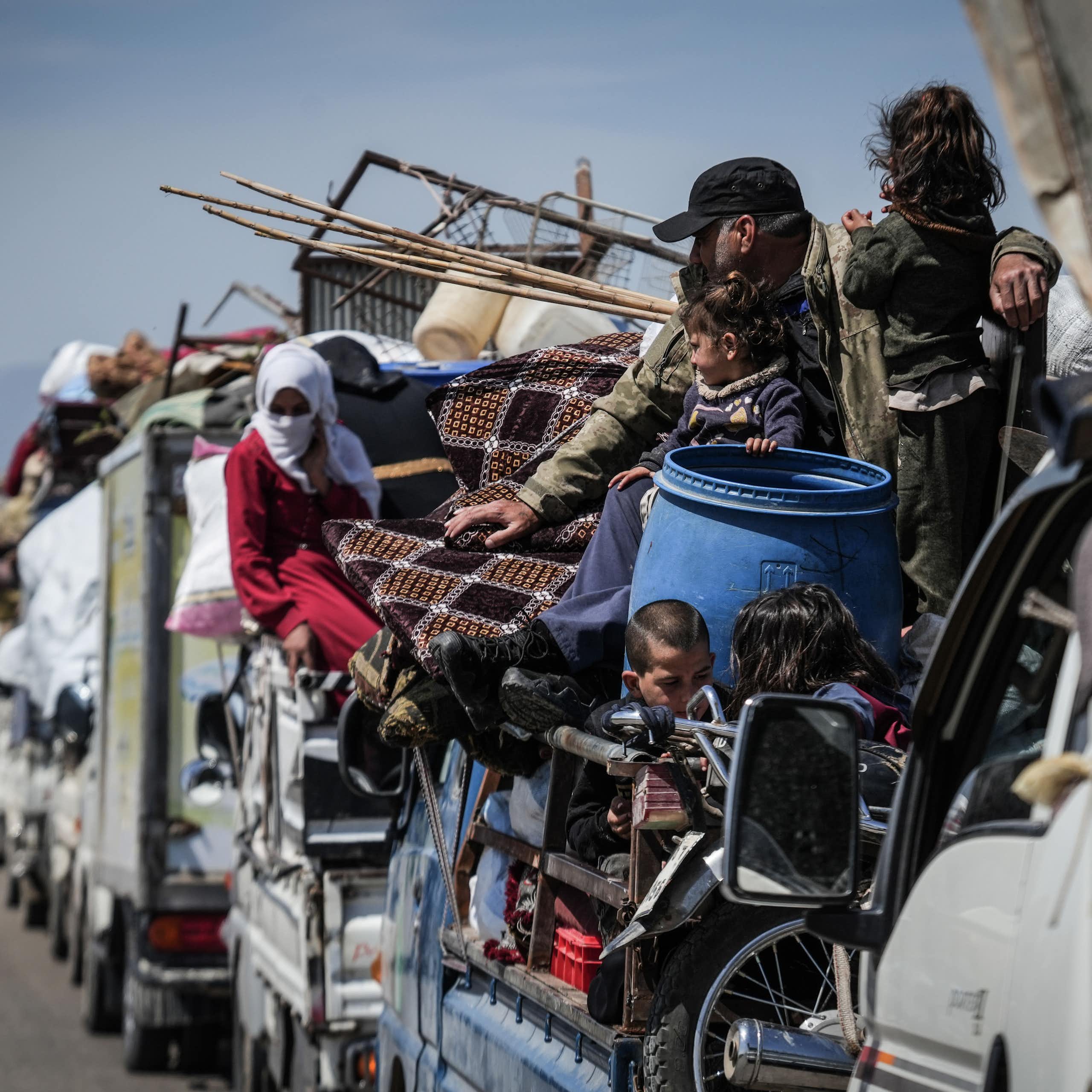 Mena and women crowd onto a convoy of vehicles.