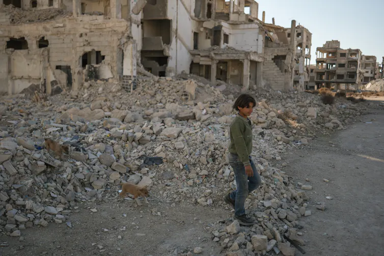 A child walks through rubble.