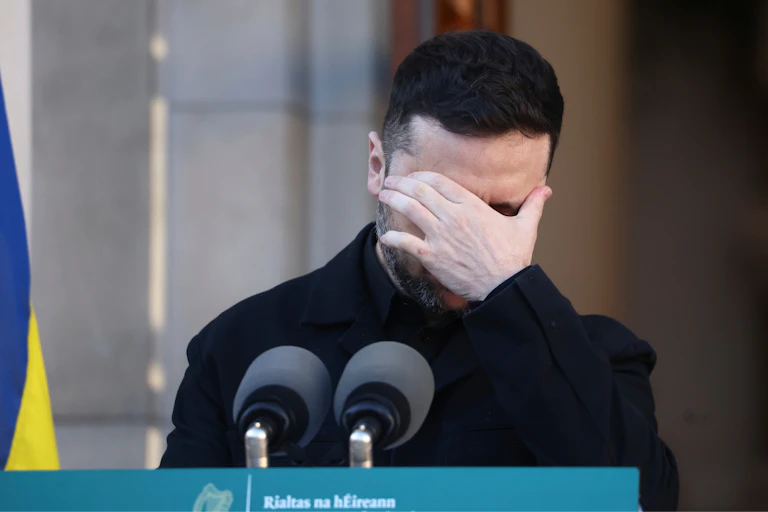 A dark-haired man with his hand over his eyes.