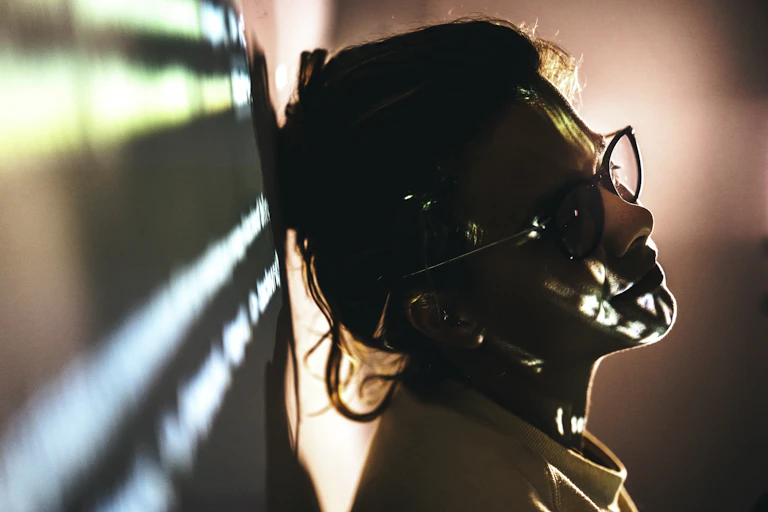 A woman who appears to be tired and possibly sad while doing her job leans against a wall.