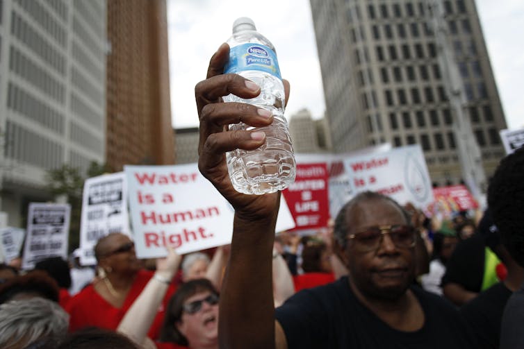 Man holds up water bottle.