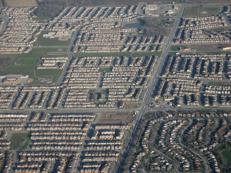 An overhead shot of a neighborhood made up of neat lines of houses and roads.