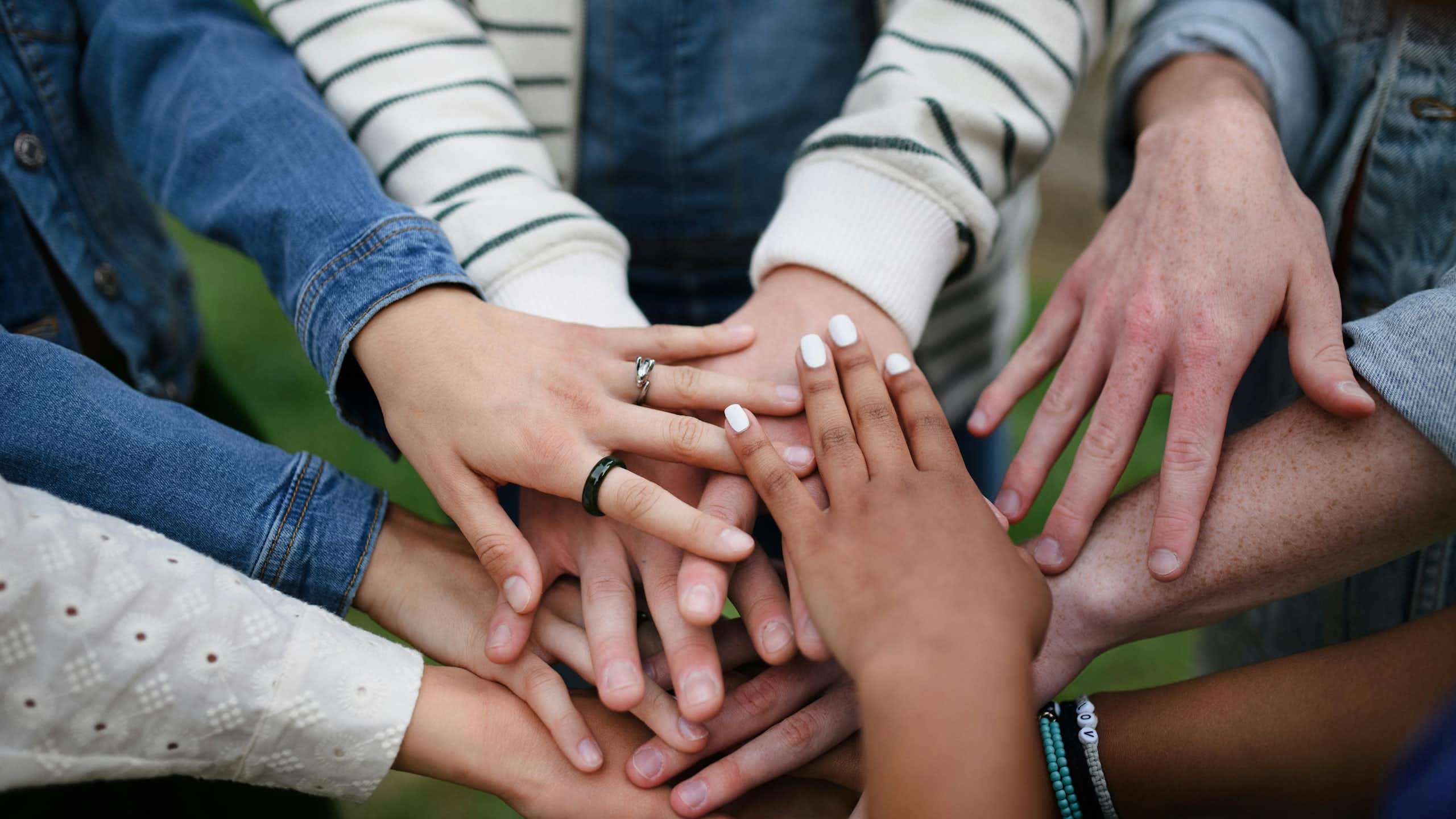 A group of people putting their hands together while standing in a circle