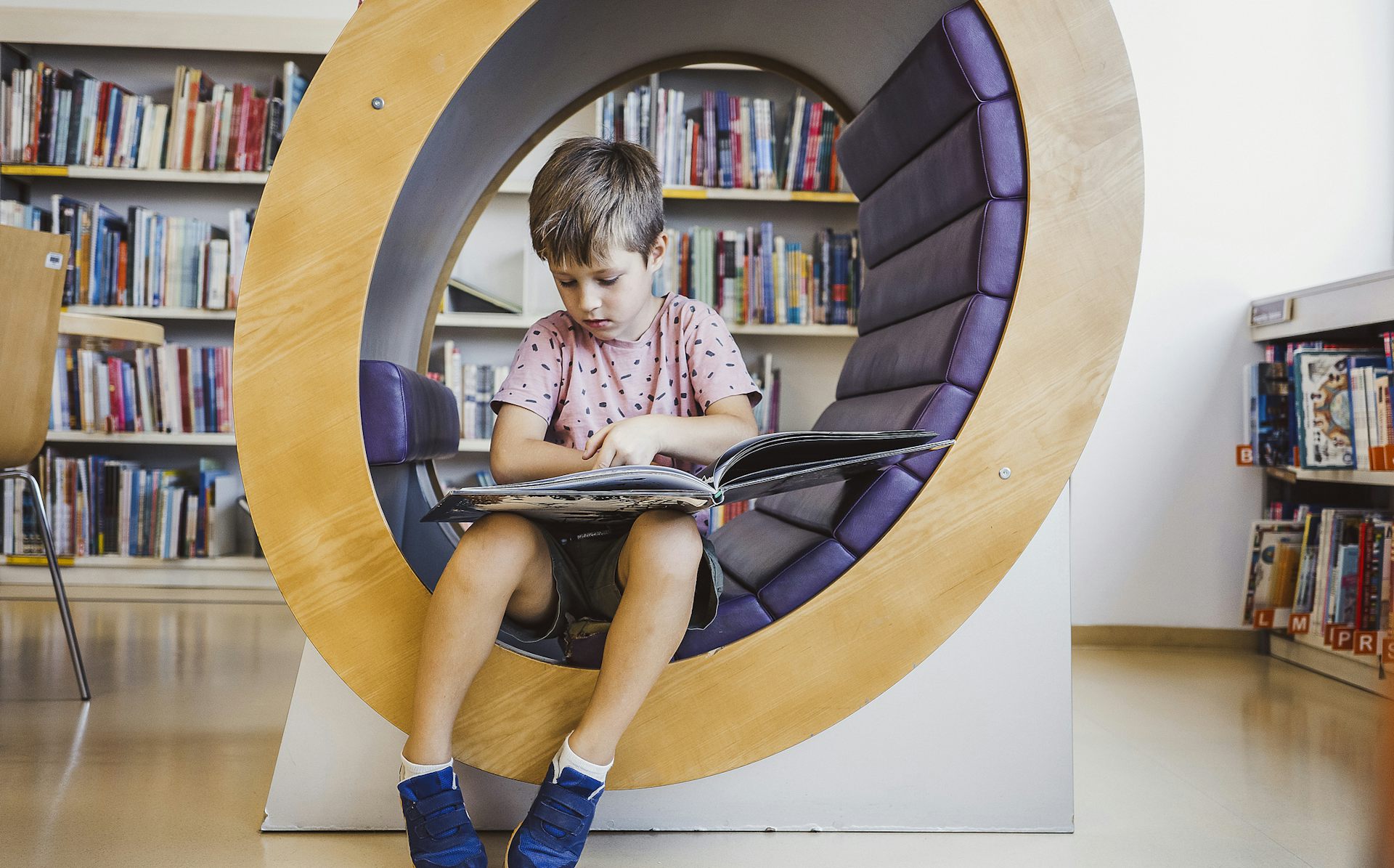 A child sits in a reading nook in a library.