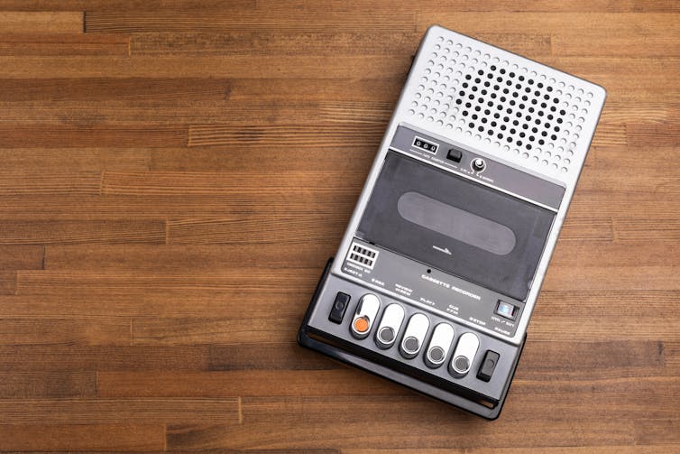 Silver coloured casette recorder on wooden table.