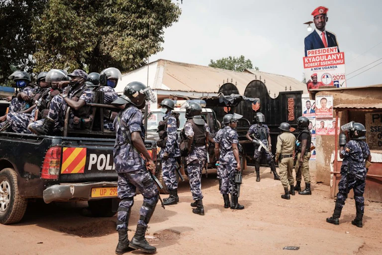 Armed police in camouflage uniform take position outside a gated compound.