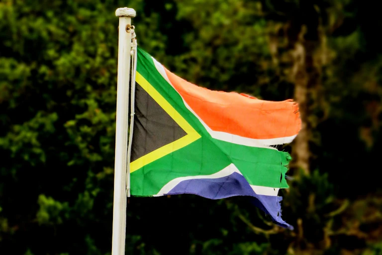 A battered and torn South African flag flaps in the wind.