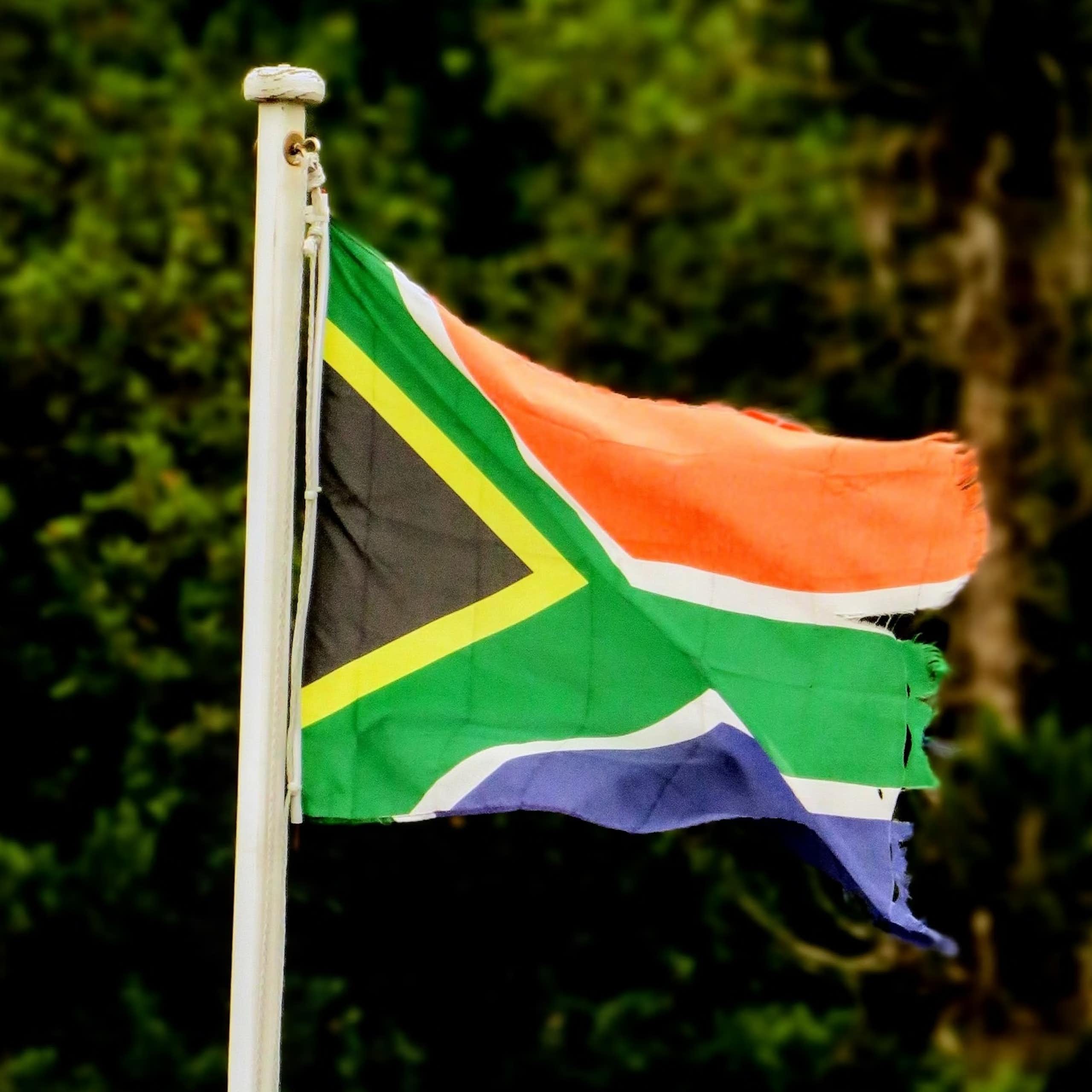 A battered and torn South African flag flaps in the wind.