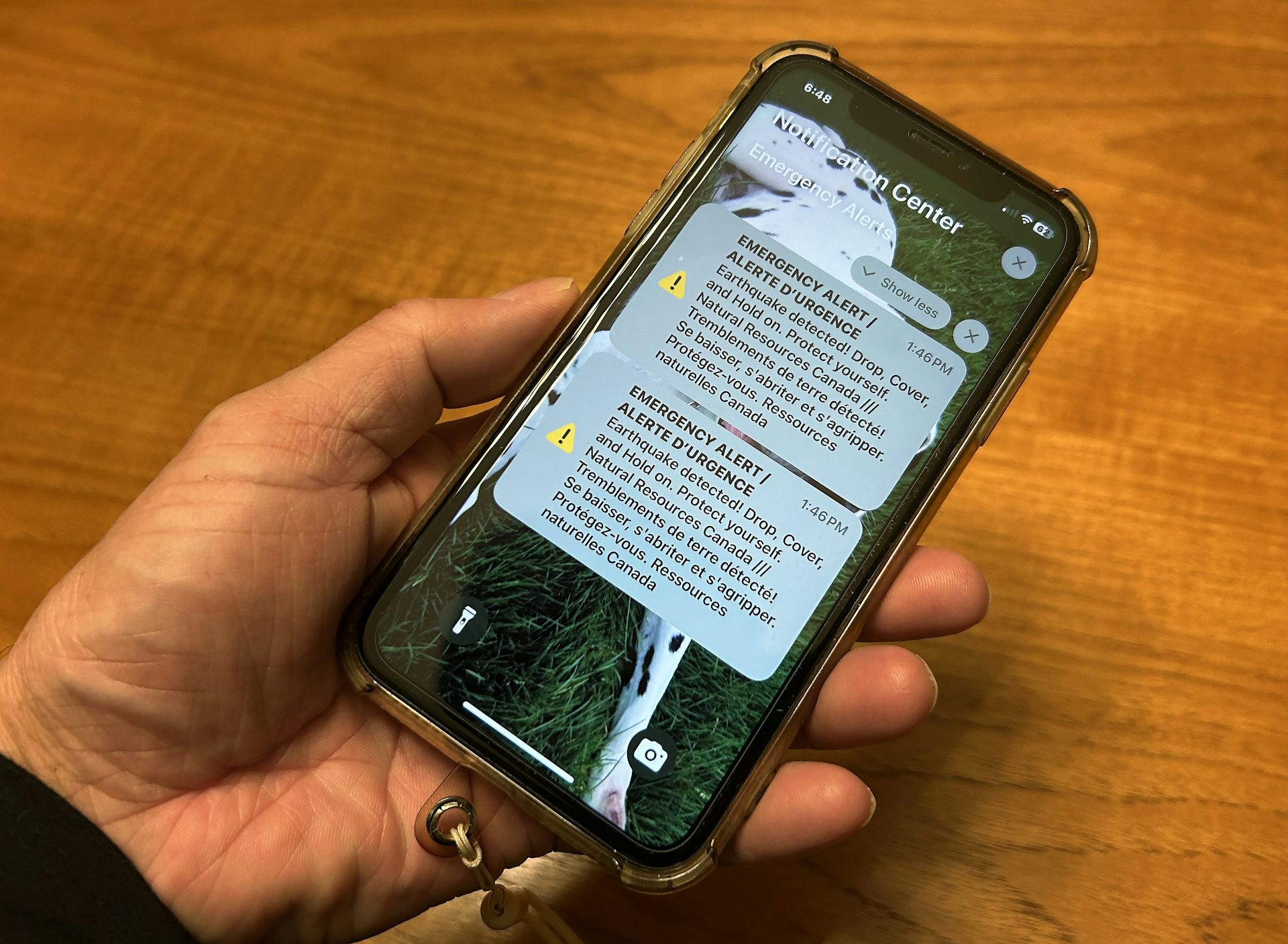 A person holds a cell phone showing an emergency alert.