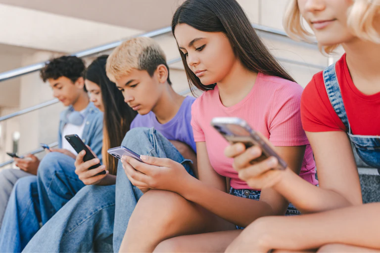A row of teenagers all using their phones.