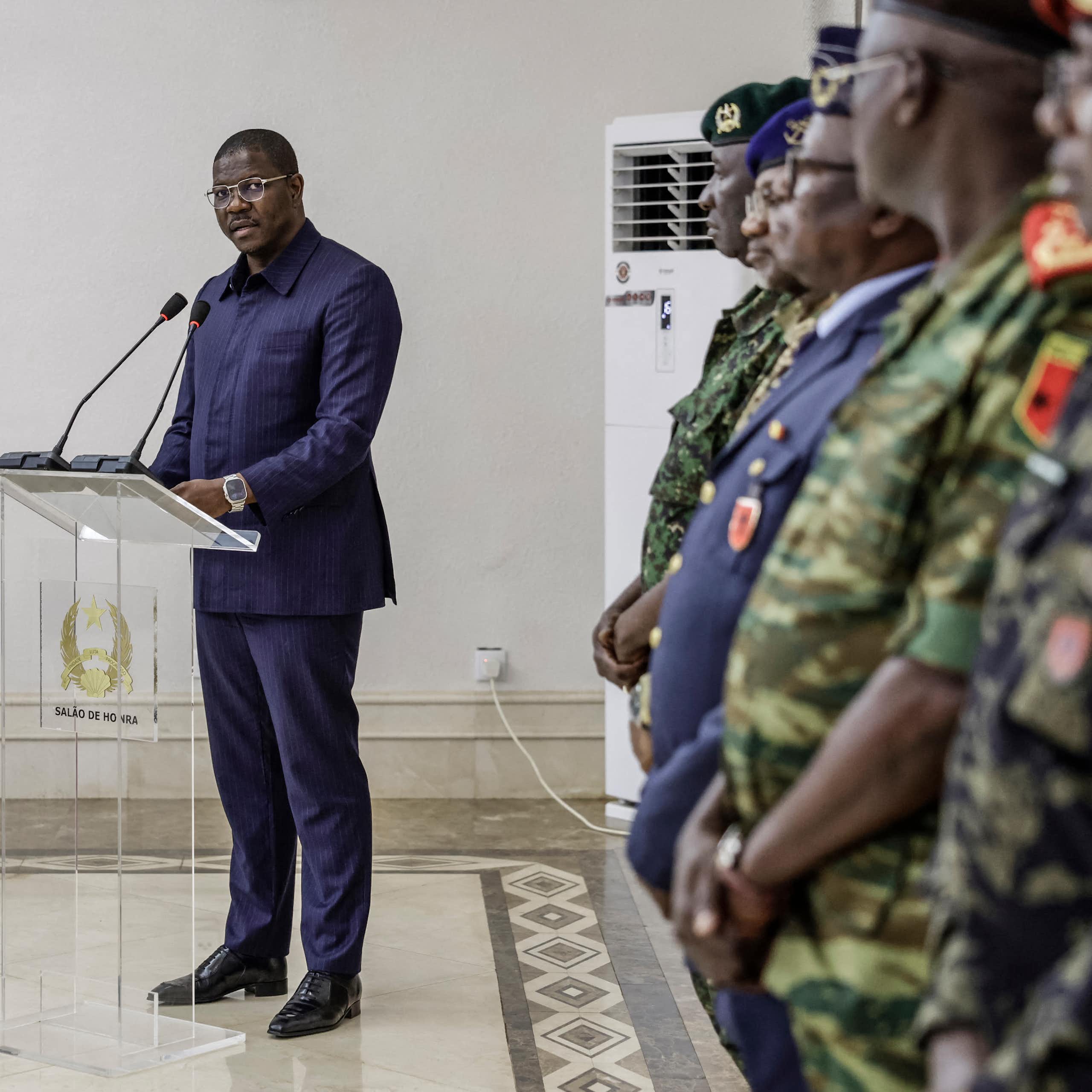 A man standing at a podium in front of military officers