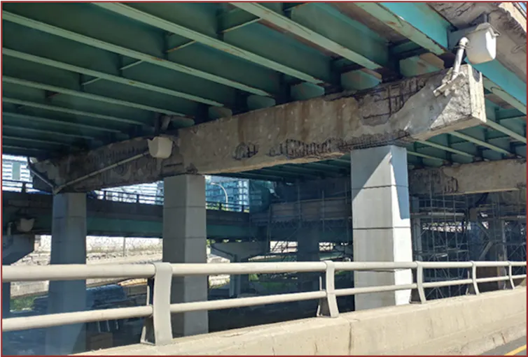 a cracked concrete slab on pillars below an elevated roadway