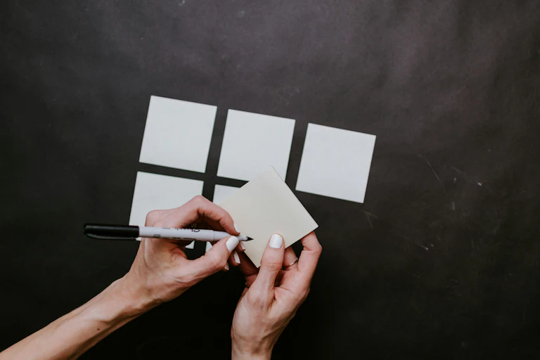 A view of someone's hands writing on post-its.