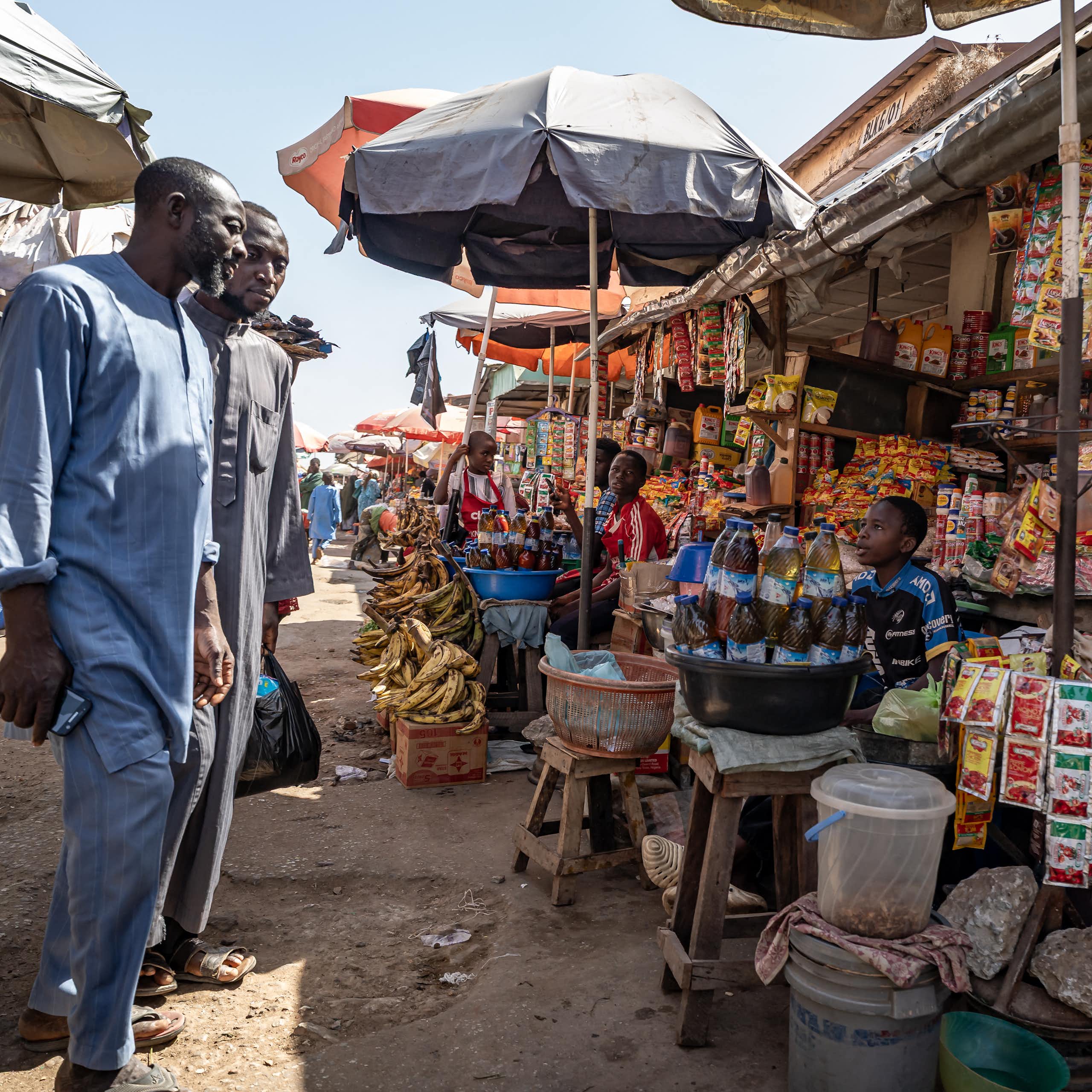 Two men looking at displays of goods at an informal market