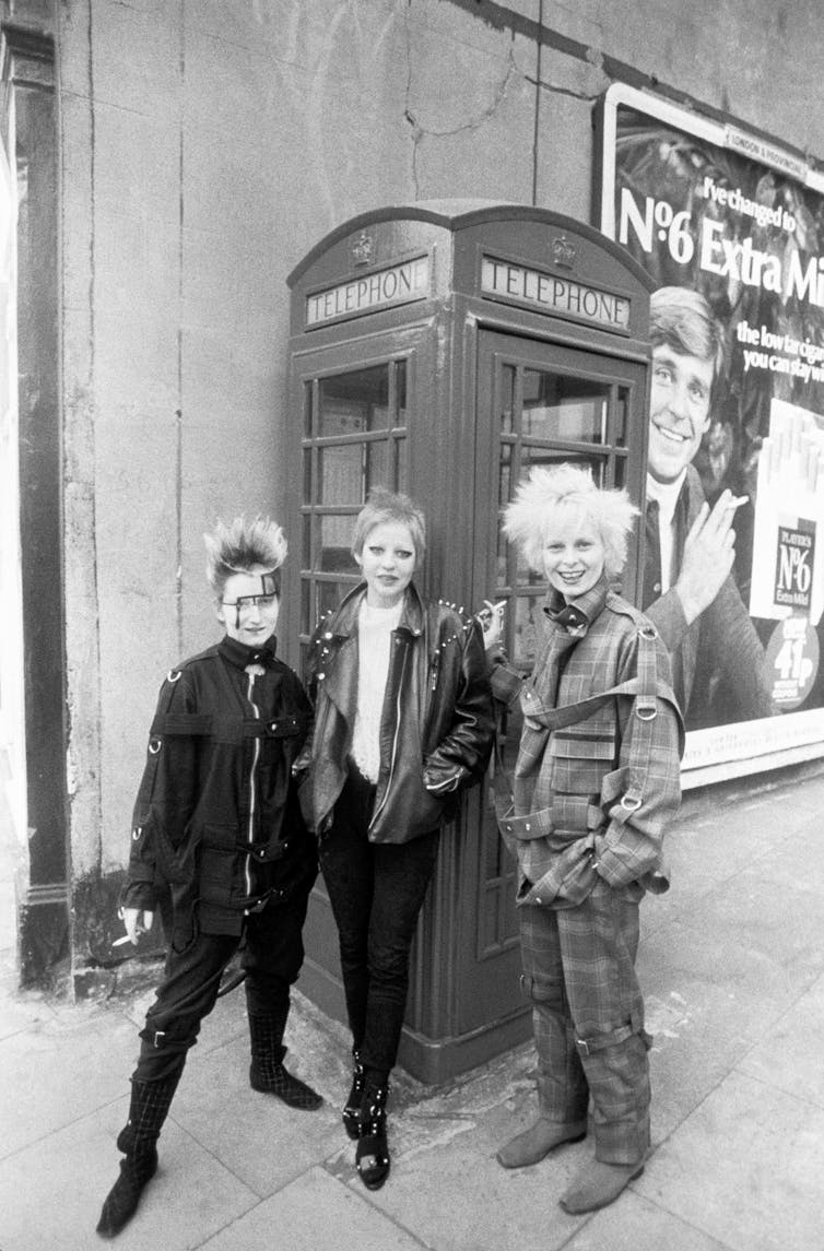 Black and white photo of three women in front of a London telephone booth.