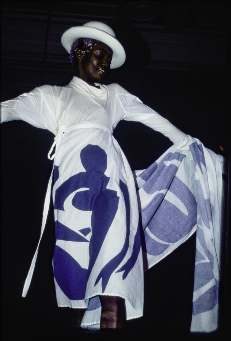 A model in a white dress with blue figures on it.