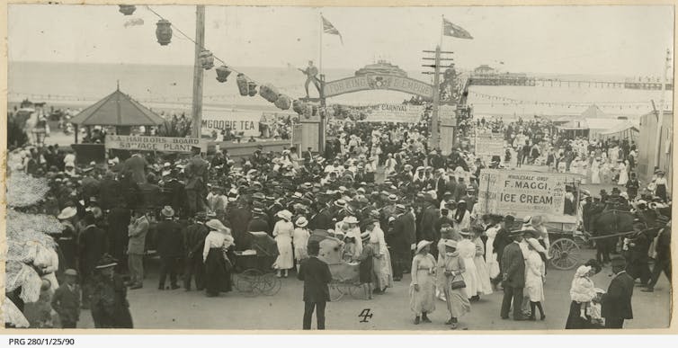 A huge crowd, jetty is decorated with a patriotic archway, Chinese lanterns and coloured lights.