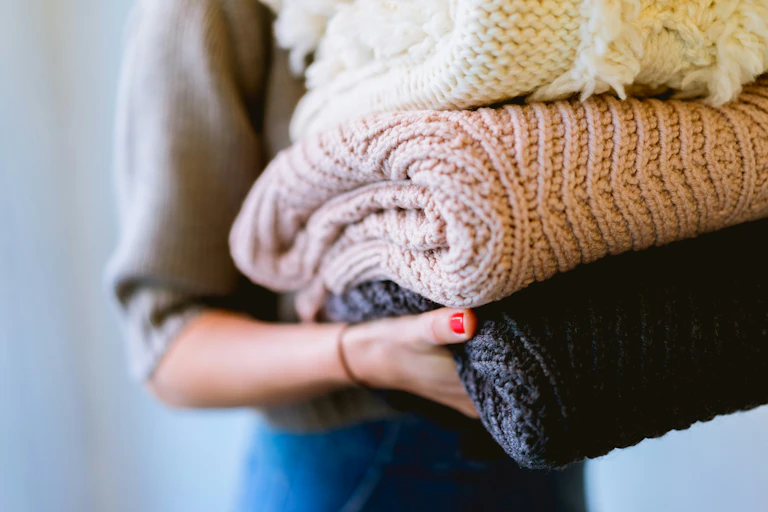 Woman holding folded knitwear