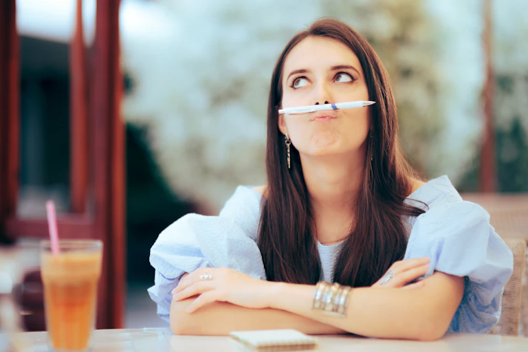 Woman playing with her pen, procrastinating her task.