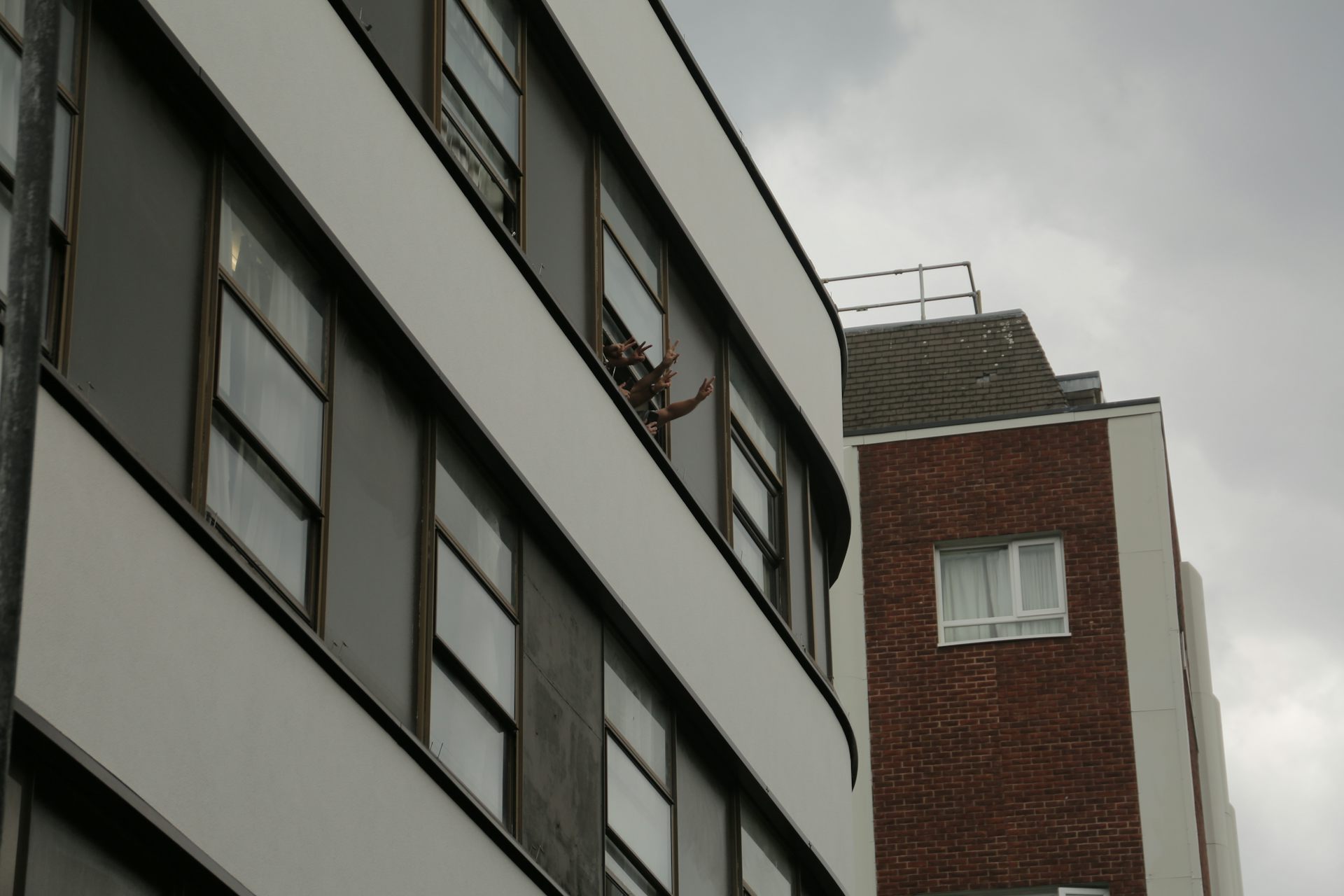 Asylum seekers waving out of the window of a hotel in London.