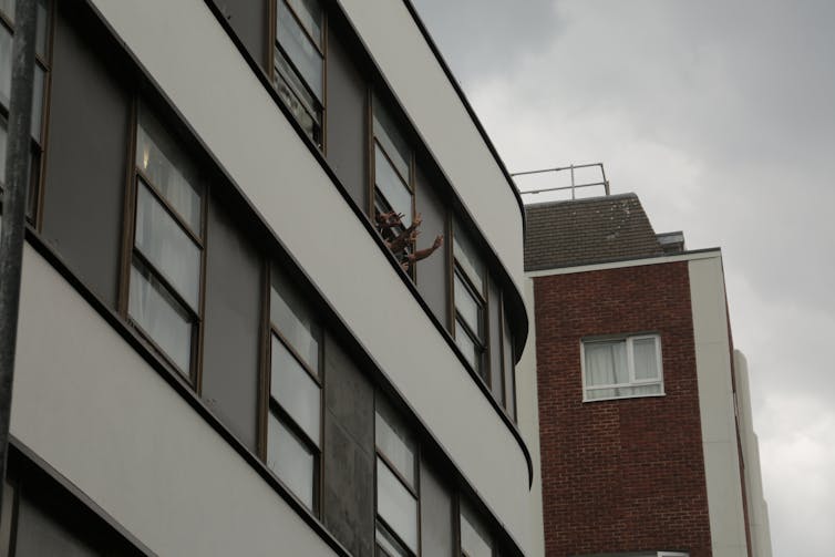 Asylum seekers waving out of the window of a hotel in London.