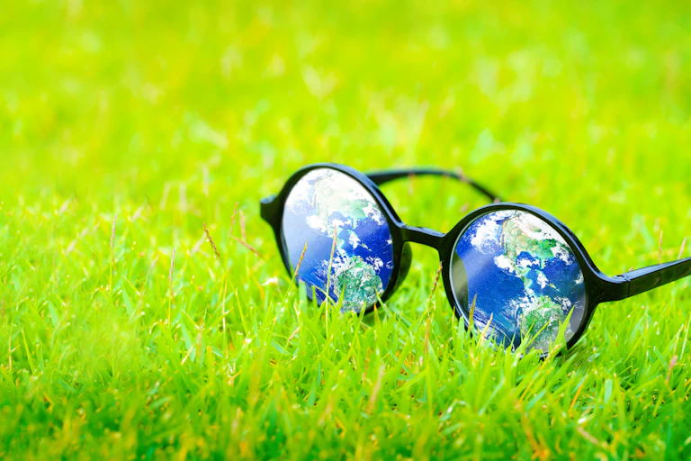 glasses with reflection of planet earth, on grass
