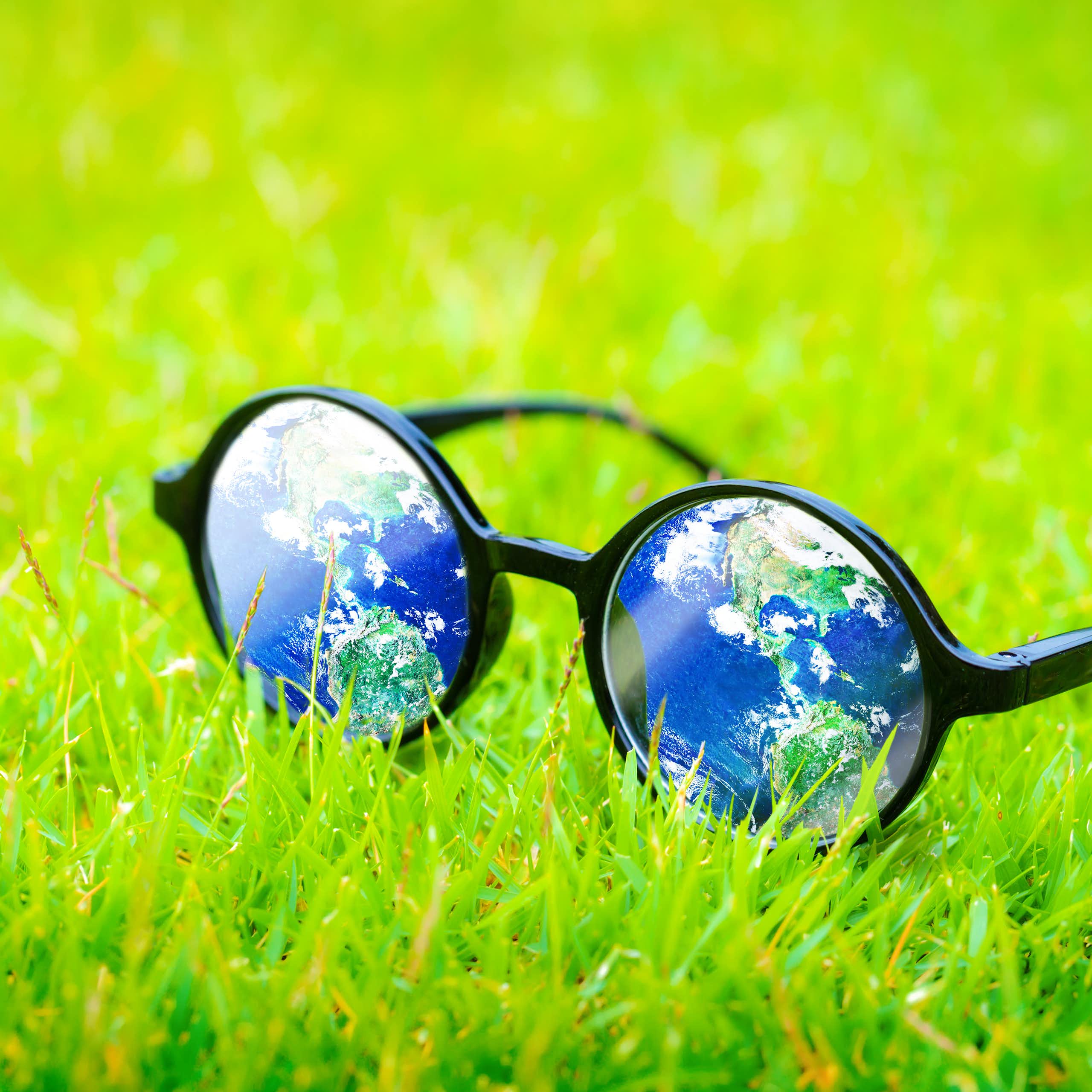 glasses with reflection of planet earth, on grass