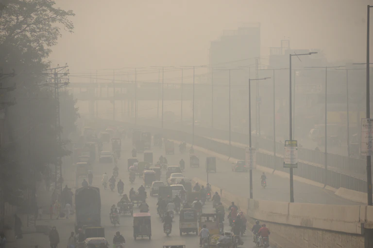 Photo of commuters make their way along a road amid smoggy conditions in Lahore, Pakistan.