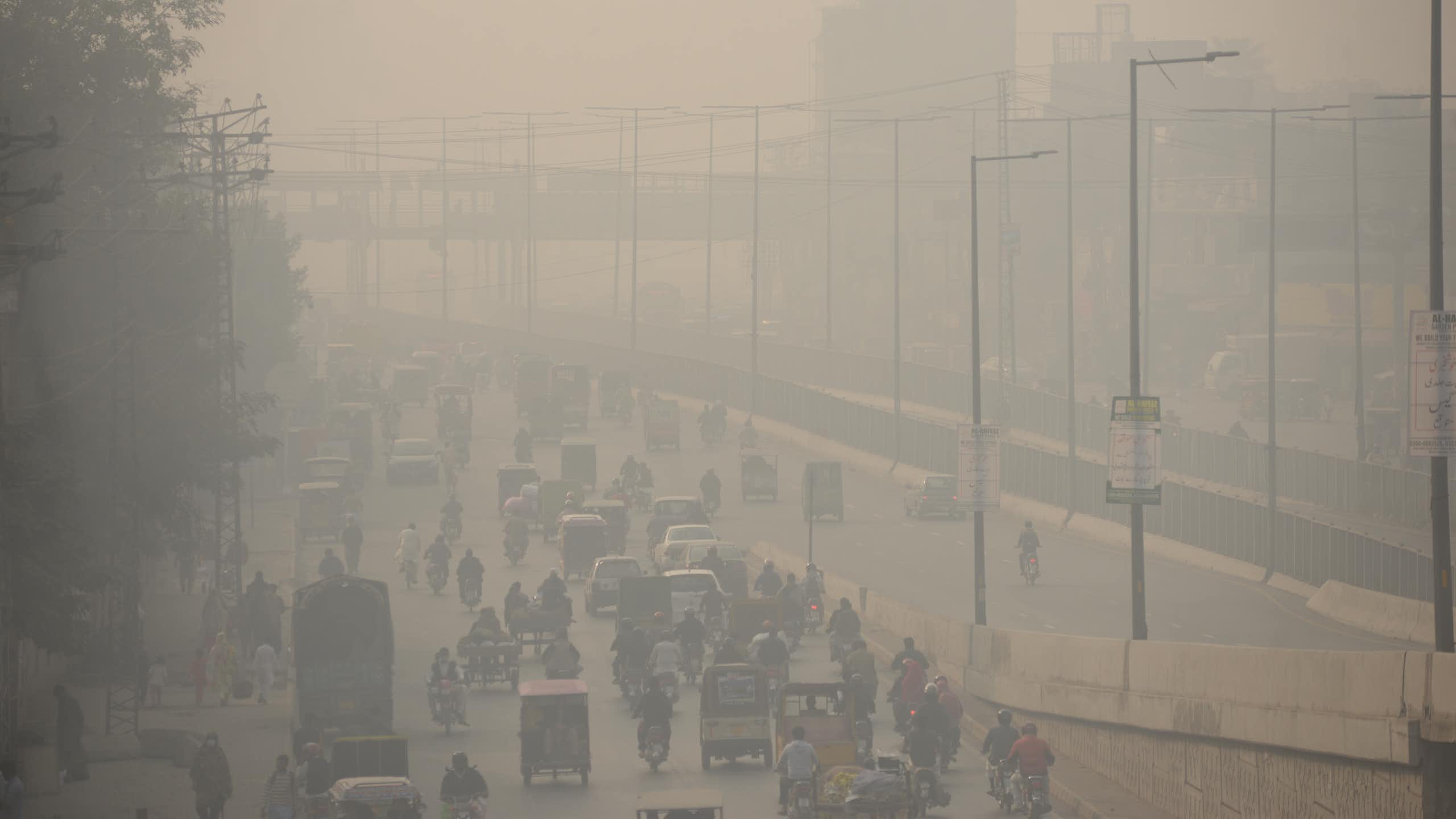 Photo of commuters make their way along a road amid smoggy conditions in Lahore, Pakistan.