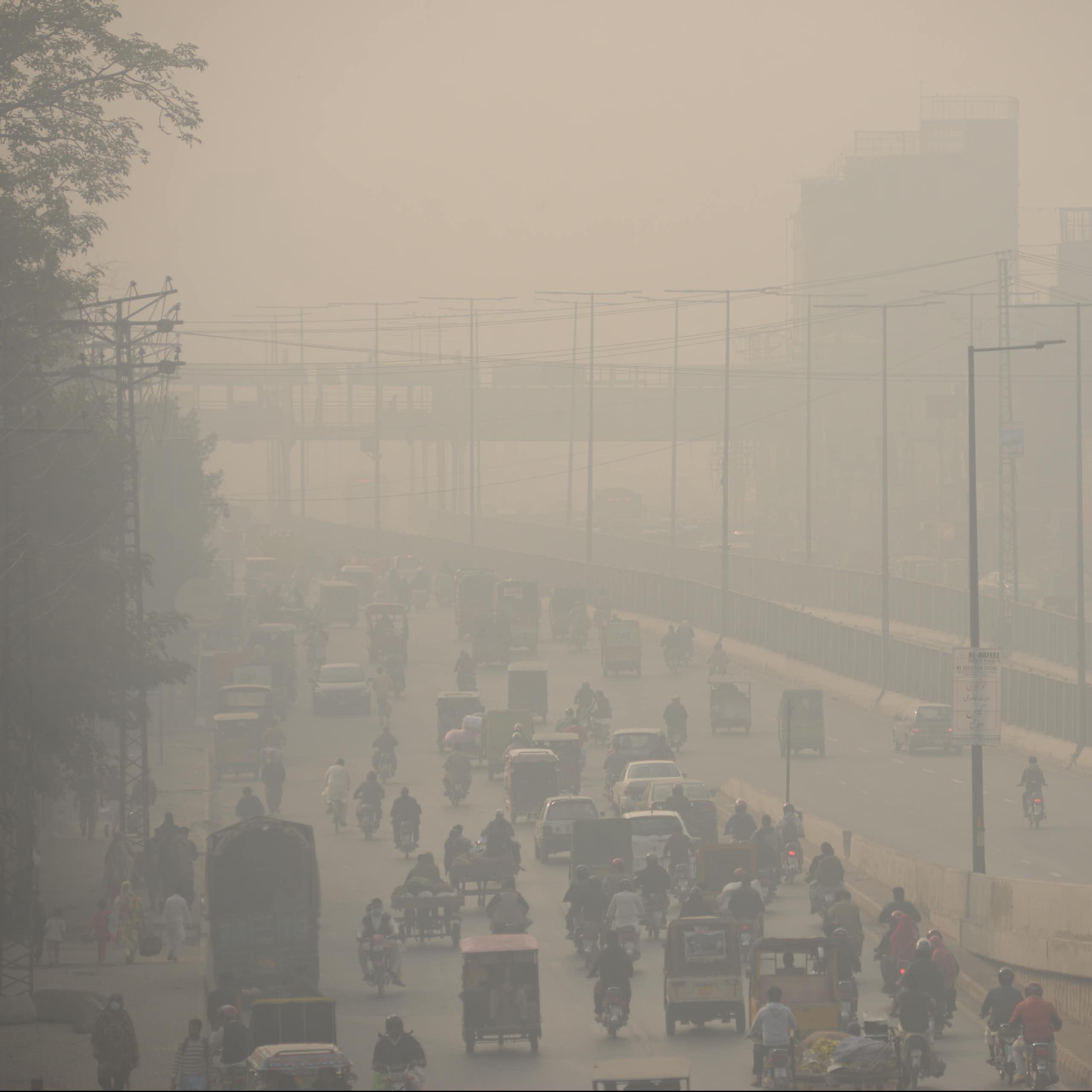 Photo of commuters make their way along a road amid smoggy conditions in Lahore, Pakistan.