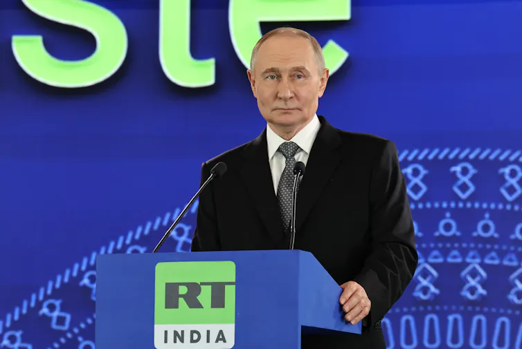 Putin standing at a podium with the RT India logo