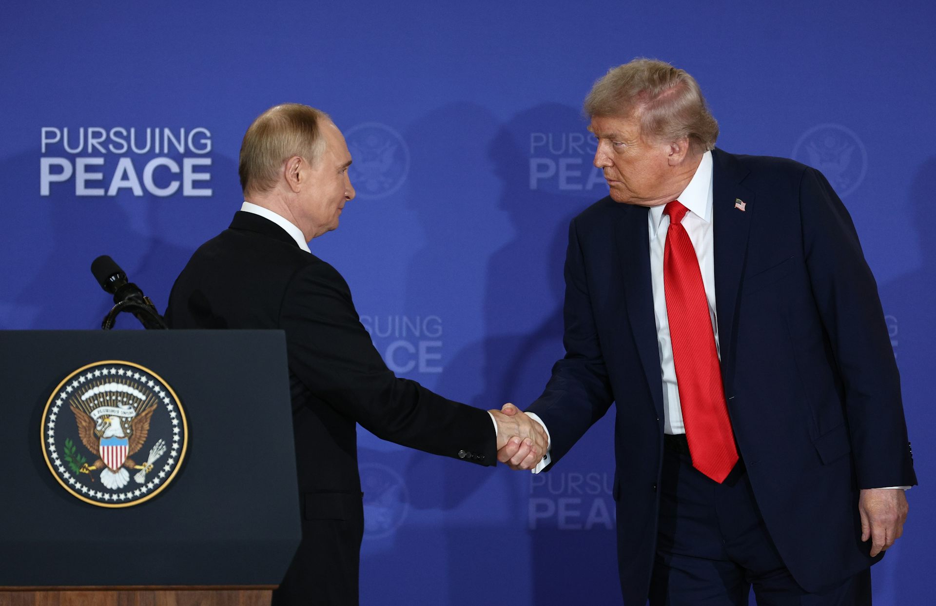 Donald Trump shakes hands with Vladimir Putin