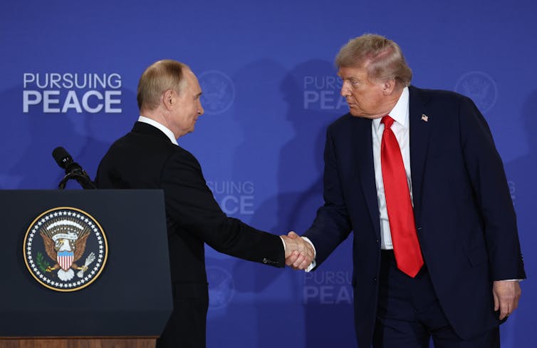 Donald Trump shakes hands with Vladimir Putin