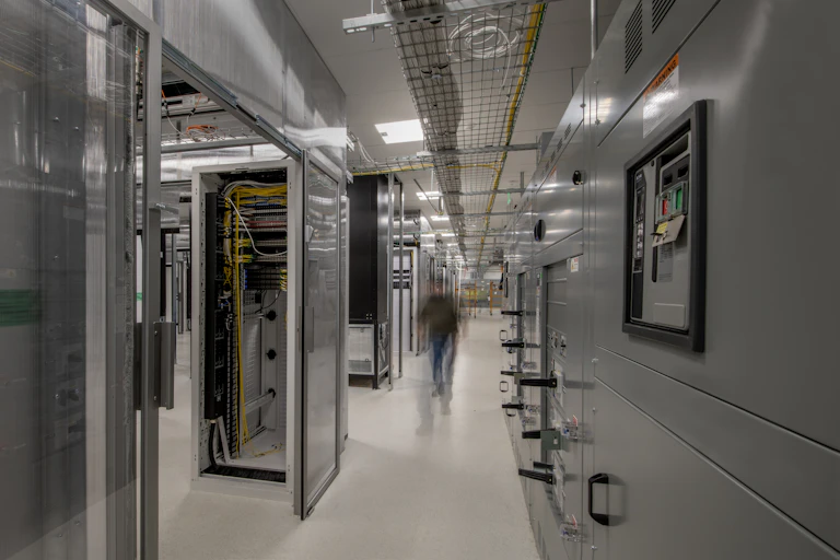 A person walks through a large area filled with metal containers of electronics.