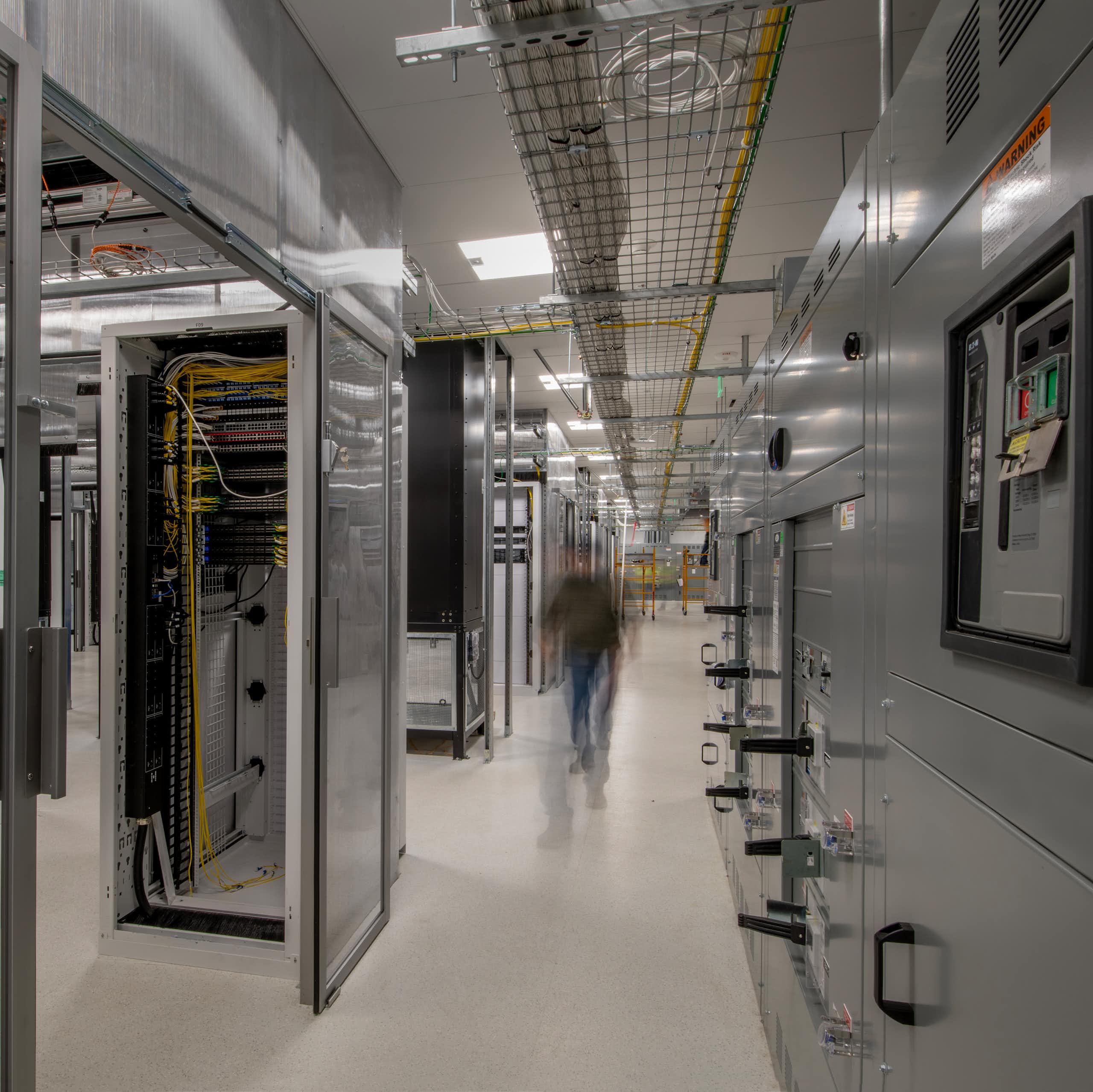 A person walks through a large area filled with metal containers of electronics.