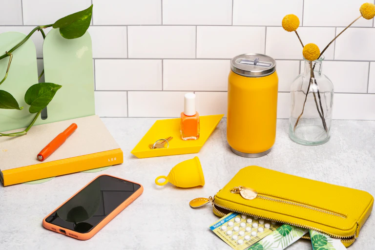 Un téléphone, un diva cup et des pilules contraceptives sont étalées sur une table