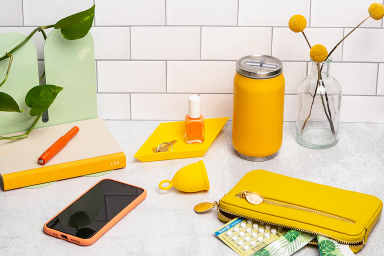 Un téléphone, un diva cup et des pilules contraceptives sont étalées sur une table